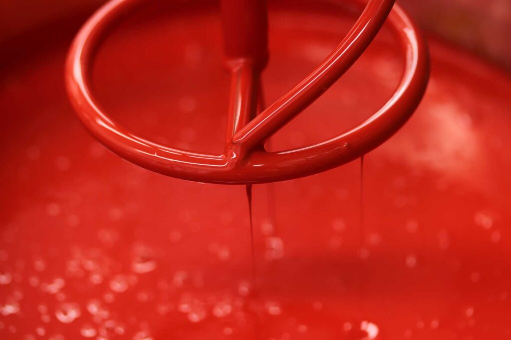 mixer in large vessel of red paint